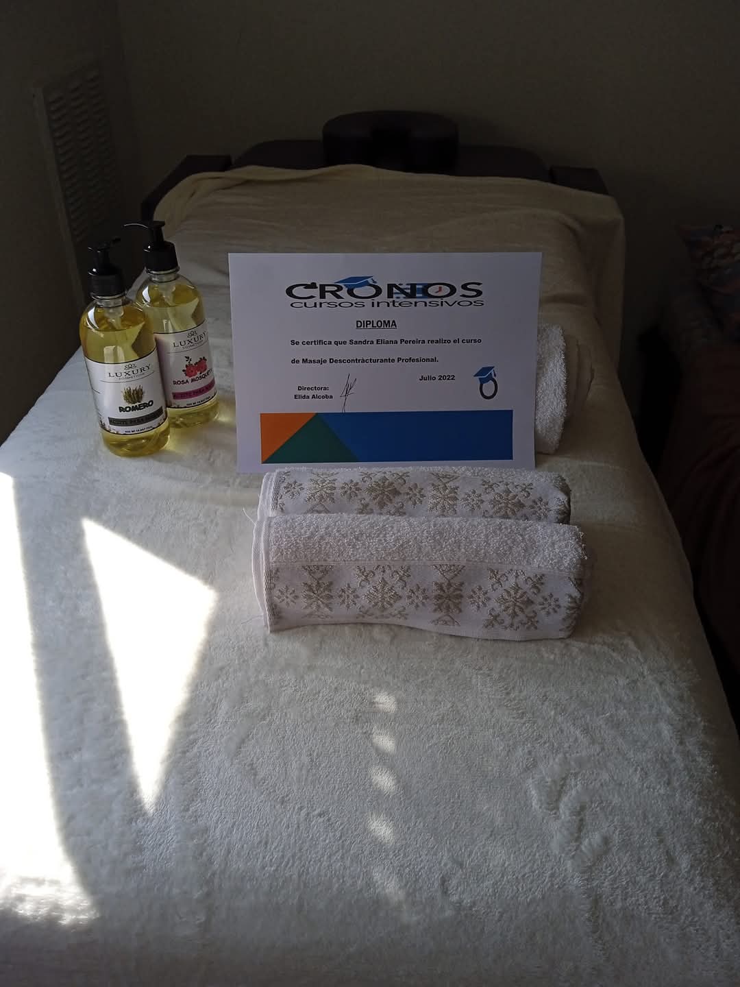 Diploma profesional CRONOS, aceites premium y toallas en la camilla de Eliana